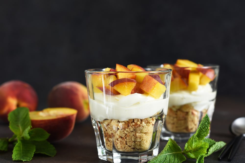 Dessert im Glas mit Pfirsichen, Keksen und Quarkcreme